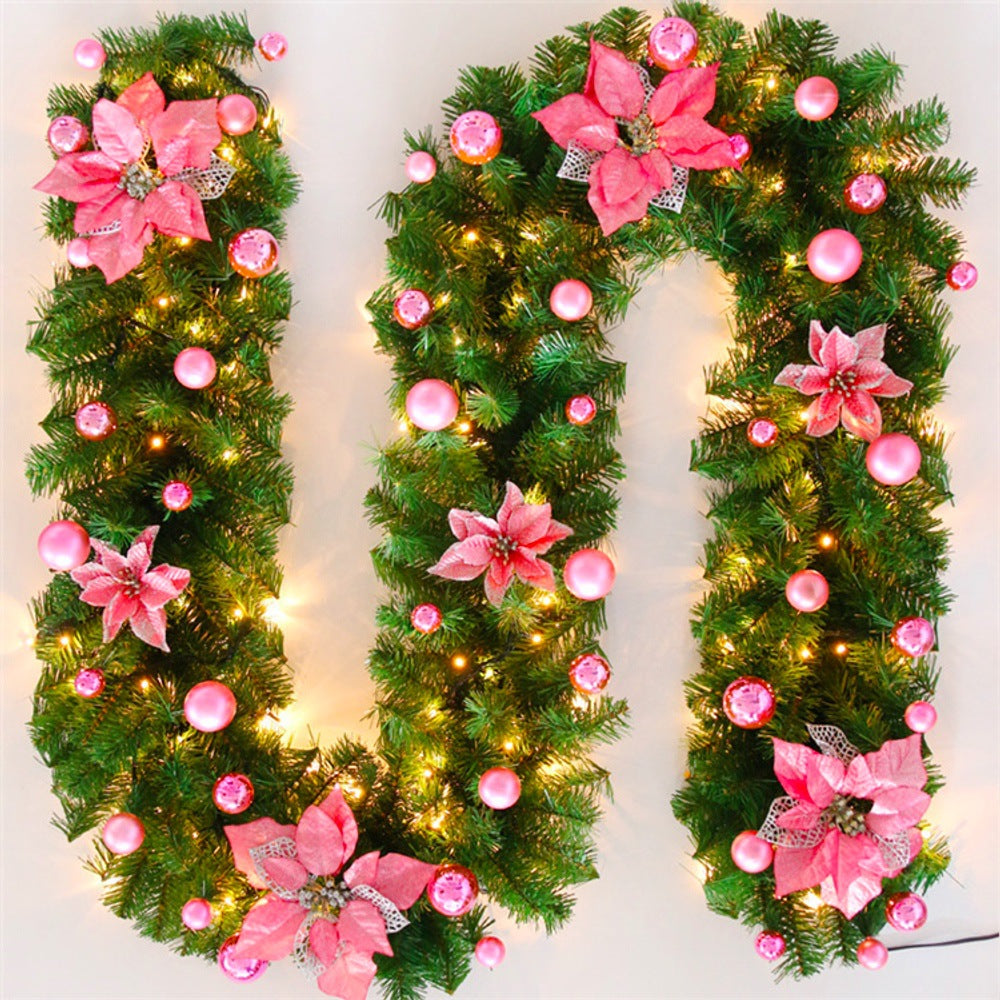 Decorative letter 'O' made of greenery with pink flowers and lights on a white background