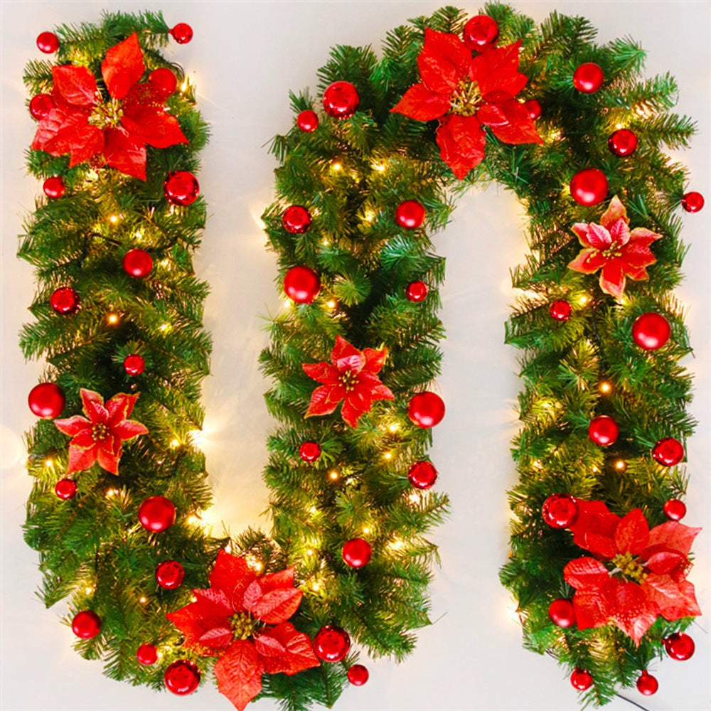 Decorative Christmas letter 'U' made of greenery, red flowers, and lights on a white background