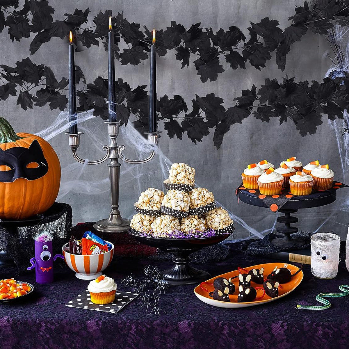 Halloween-themed table setting with popcorn tower, pumpkins, and decorative elements.