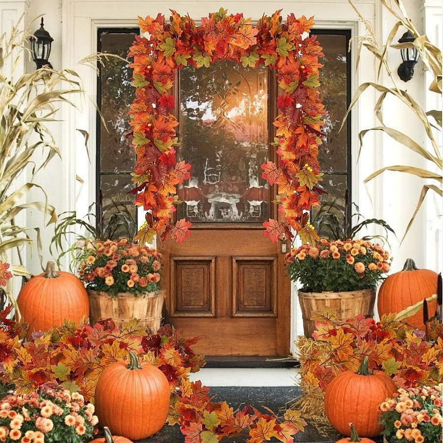 Front door decorated with autumn leaves, pumpkins, and flowers on a porch.