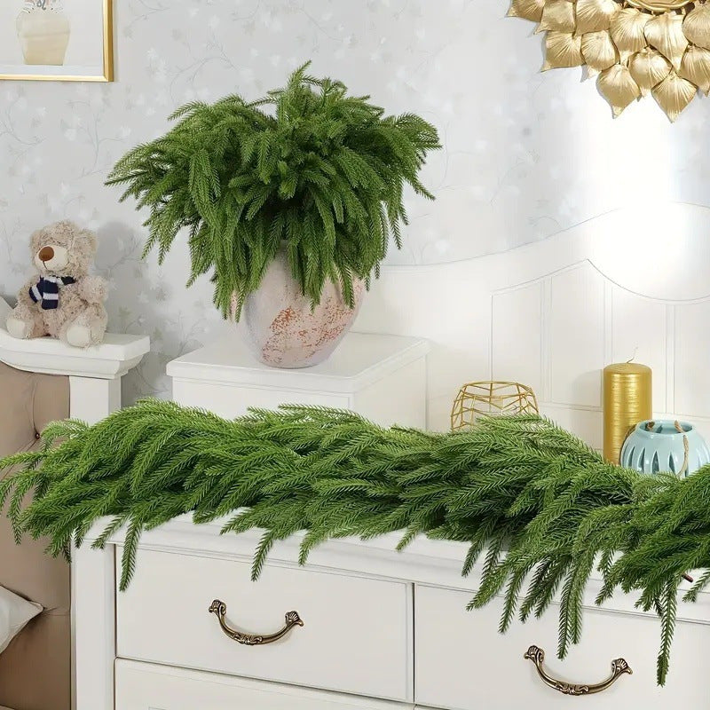 Decorative greenery on a white dresser with a teddy bear and gold lamp in the background.