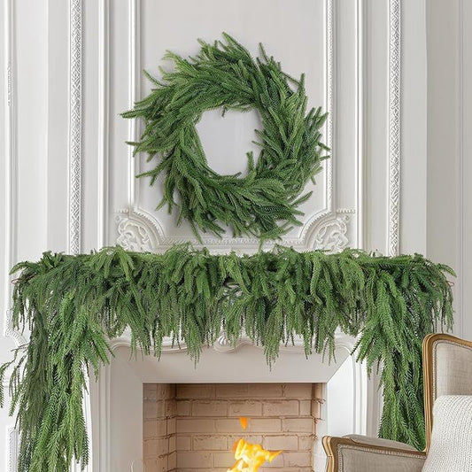 Green wreath and garland on a fireplace mantel with decorative wall paneling.